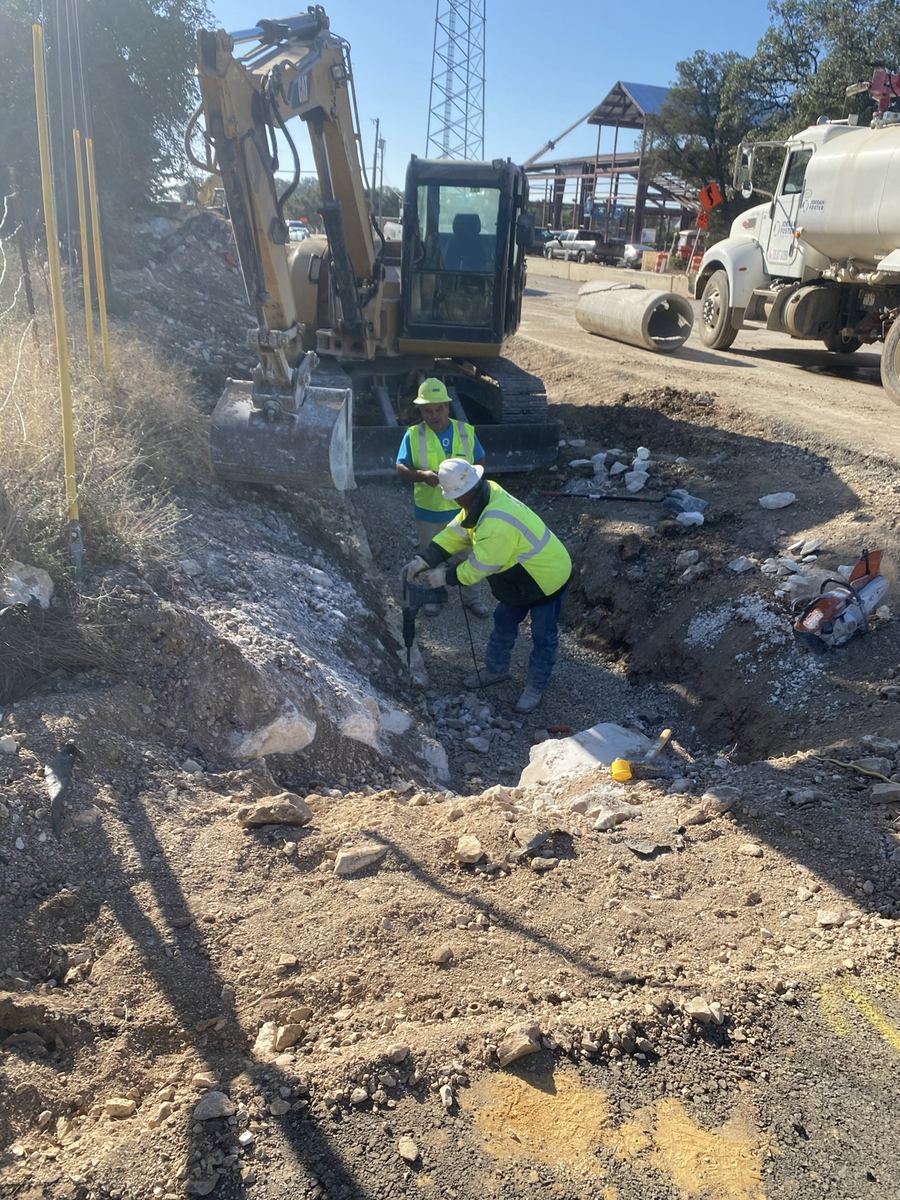 Excavator and water truck during rock excavation and site grading in the Texas Hill Country